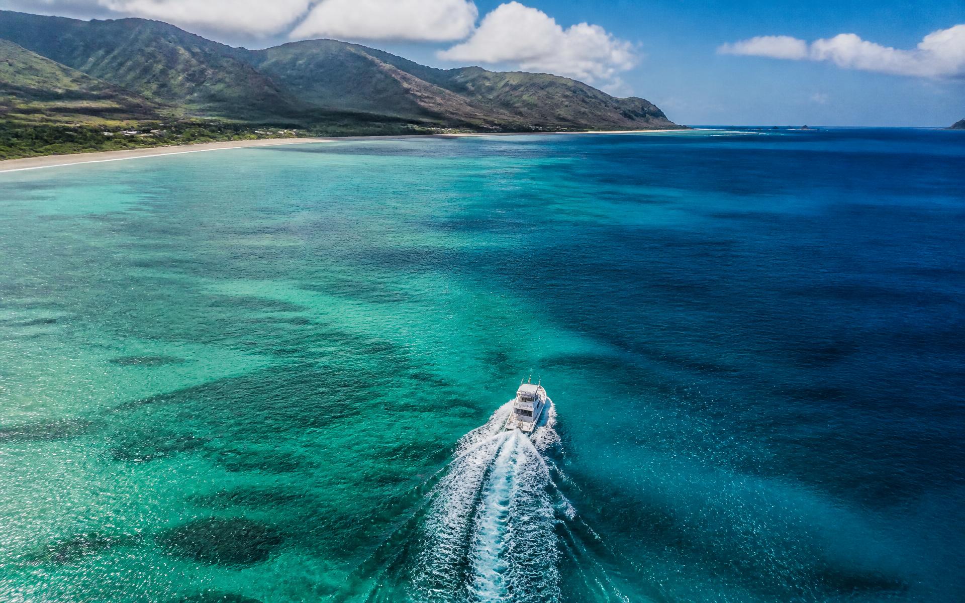Placeholder — aerial view of a boat cruising turquoise water along the Oahu coastline